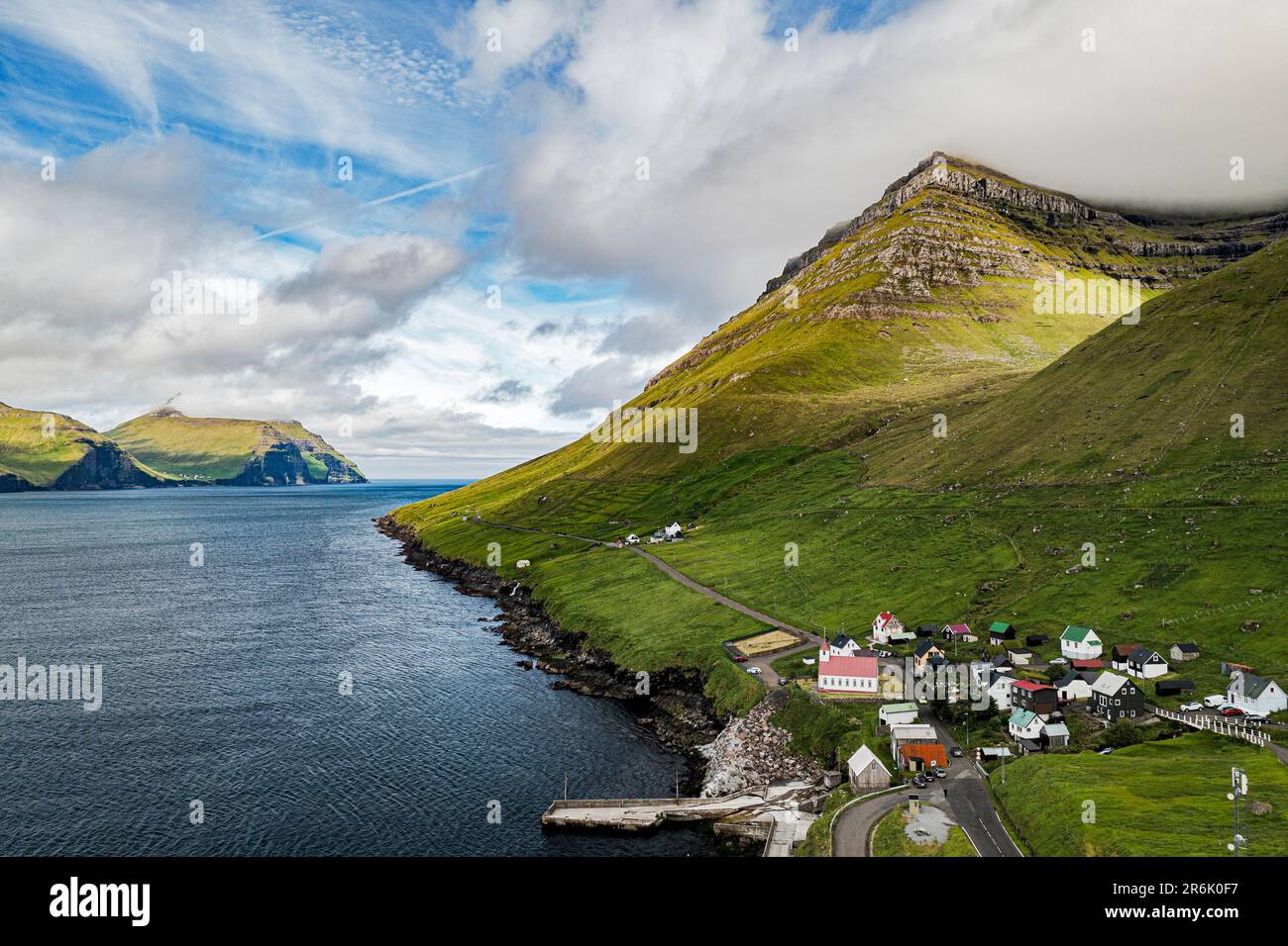Veduta aerea del villaggio costiero di Kunoy e fiordo in estate, Isola di Kunoy, Isole Faroe, Danimarca, Europa Foto Stock