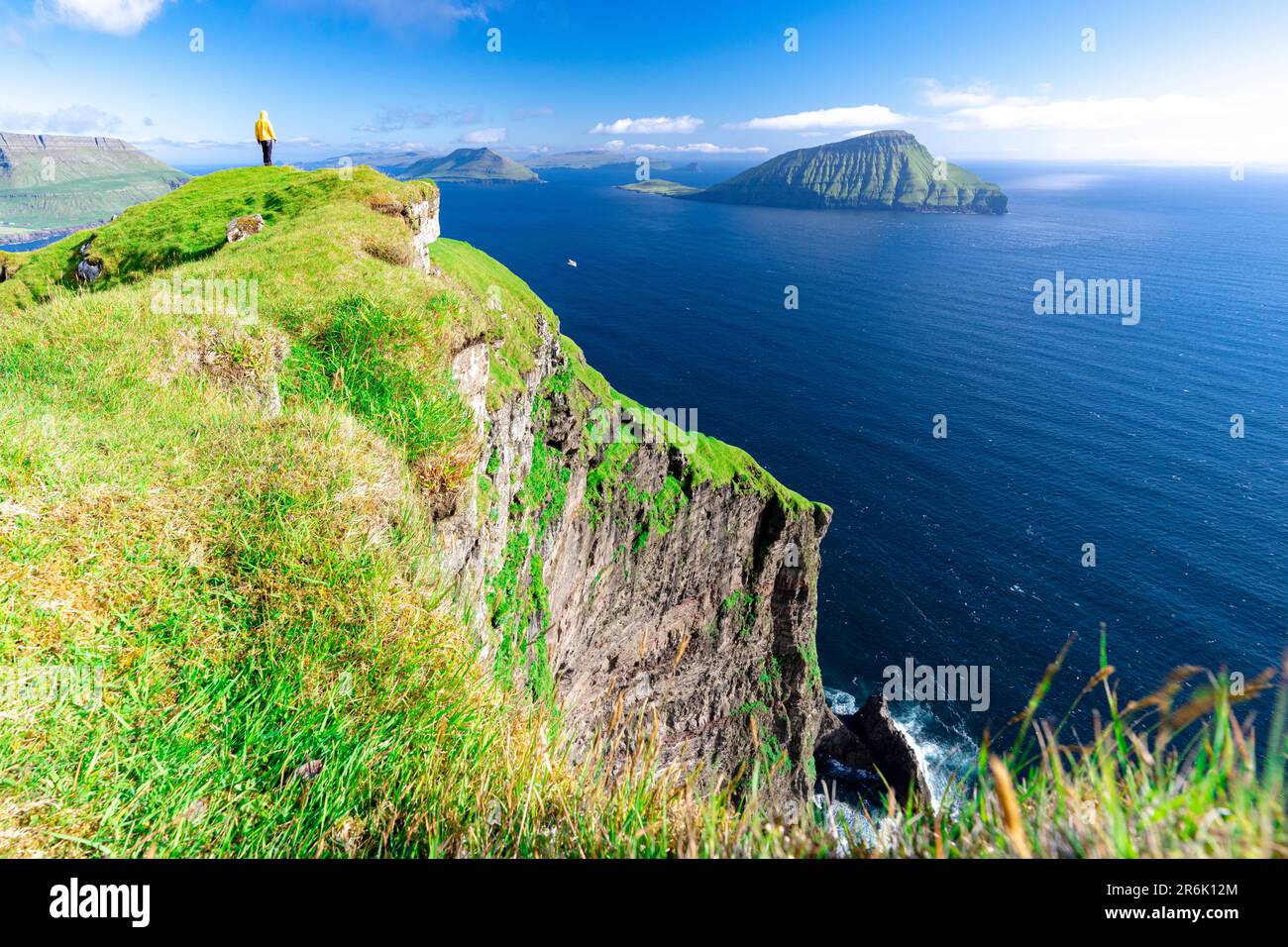 Una persona che ammira la vista che si erge sulle scogliere sopra l'oceano, Nordradalur, Streymoy Island, Faroe Islands, Denmark, Europa Foto Stock