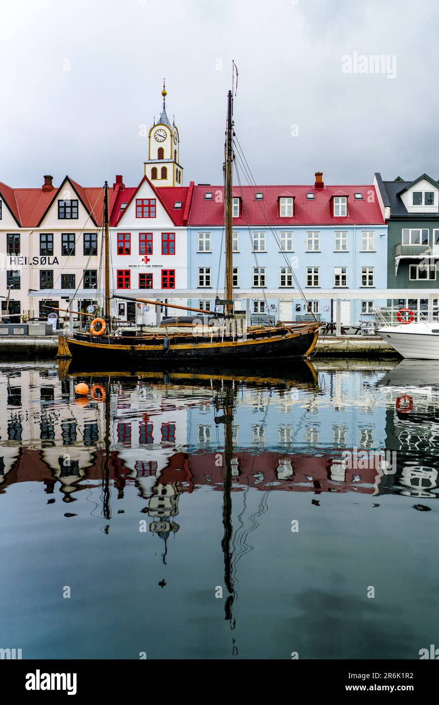 Vecchia nave in legno e colorati edifici che si riflettono nell'acqua nel porto di Torshavn, nell'isola di Streymoy, nelle isole Faroe, in Danimarca, in Europa Foto Stock