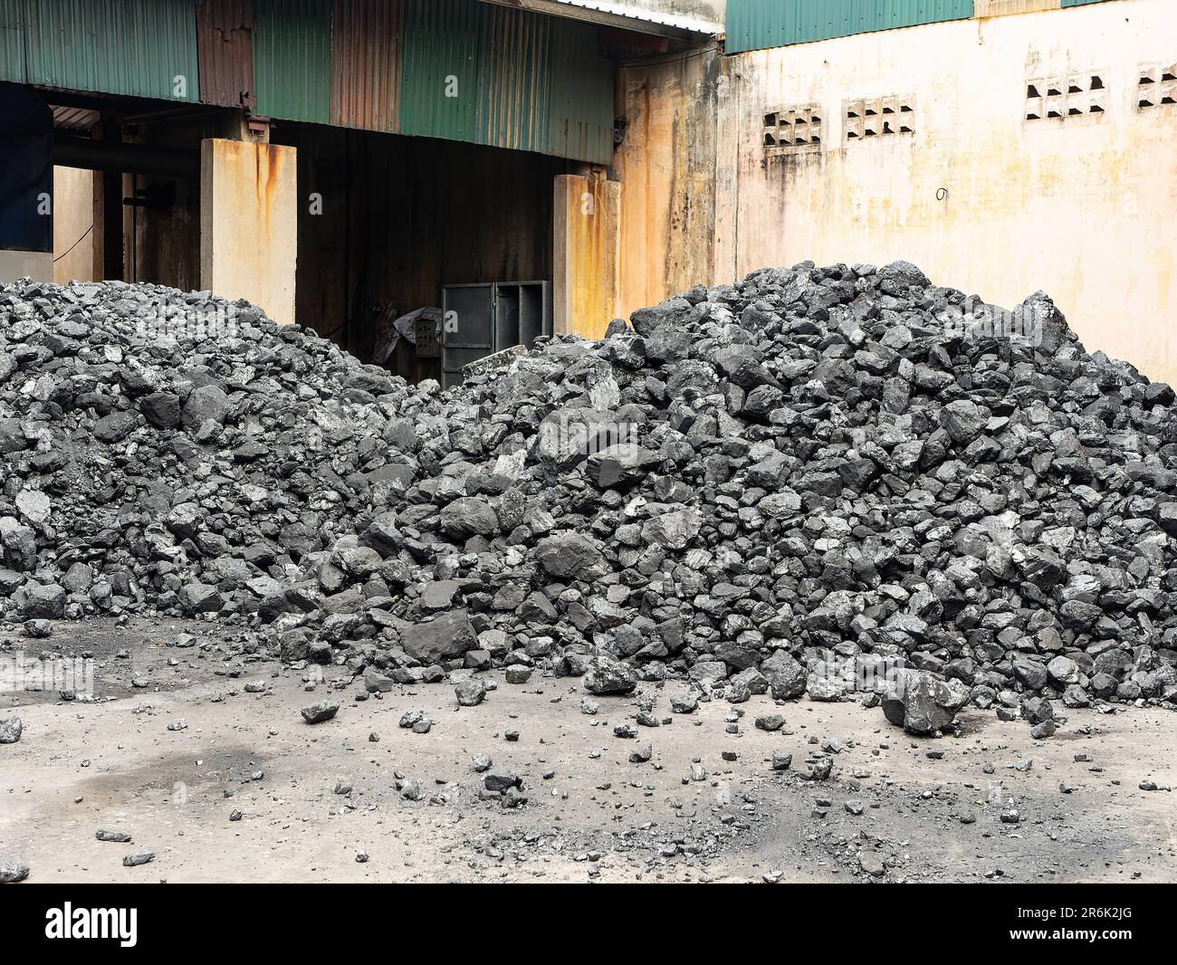 Pile di carbone nel cortile di una fabbrica in Vietnam dove viene utilizzato come combustibile per la produzione di vapore per vari processi industriali. Foto Stock