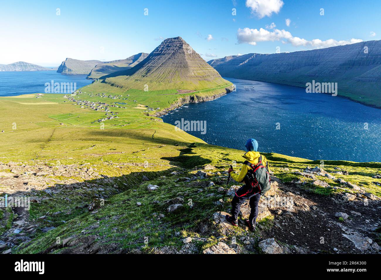 Escursionista in cima alla collina con il villaggio di Vidareidi e la montagna Malinsfjall sullo sfondo, Vidoy Island, Faroe Islands, Danimarca, Europa Foto Stock