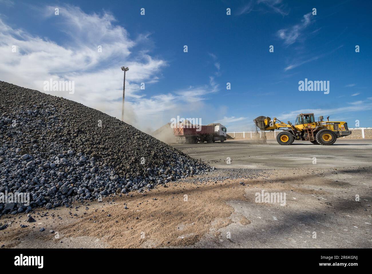 Attività di banchina: Escavatore che carica cemento nel dumper presso il porto di Laayoune Foto Stock