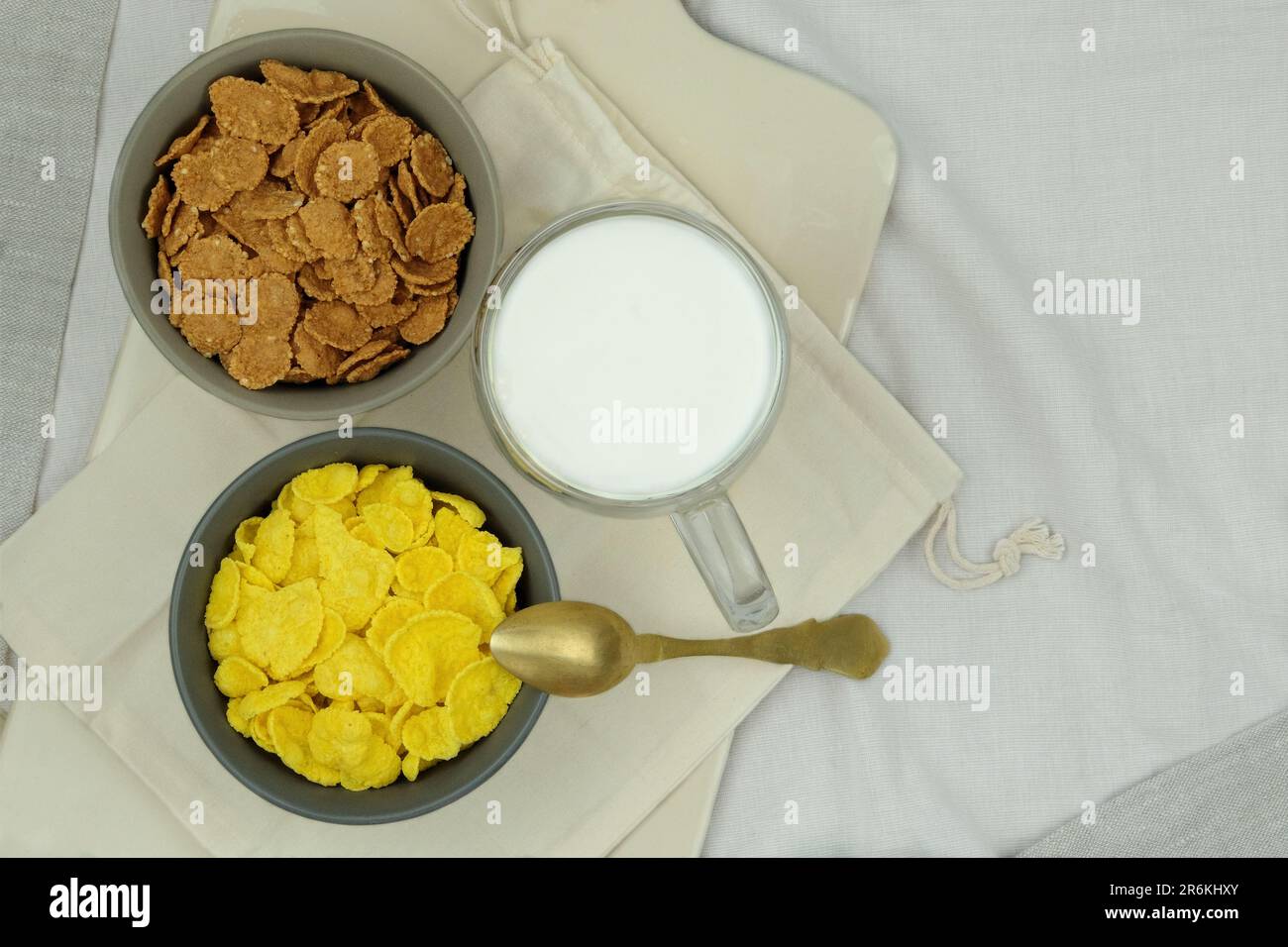 Cereali da colazione, cornflakes in ciotole e tazza di latte su sfondo chiaro. Fast food. Vista dall'alto. Foto Stock