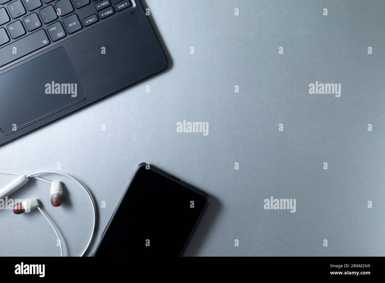L'angolo della tastiera, dello smartphone e delle cuffie si trova su un tavolo luminoso con un posto in cui copiare Foto Stock