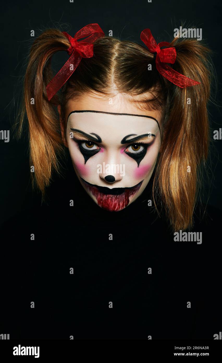 Primo piano ritratto di giovane ragazza adolescente con trucco Halloween, hairstail con due pigtail e nastri rossi, sfondo nero Foto Stock