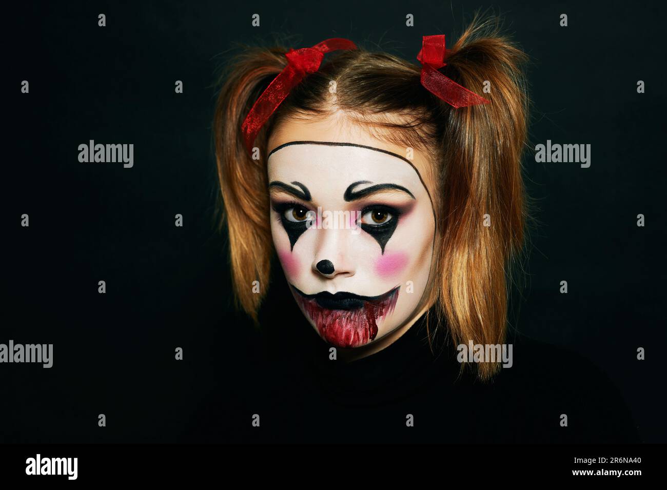 Primo piano ritratto di giovane ragazza adolescente con trucco Halloween, hairstail con due pigtail e nastri rossi, sfondo nero Foto Stock