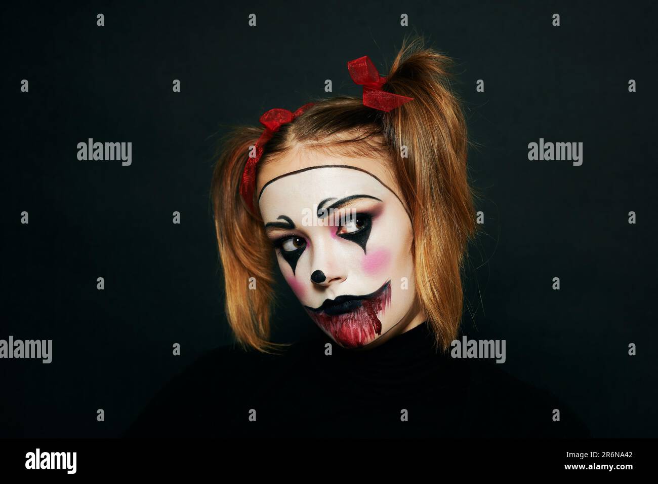Primo piano ritratto di giovane ragazza adolescente con trucco Halloween, hairstail con due pigtail e nastri rossi, sfondo nero Foto Stock