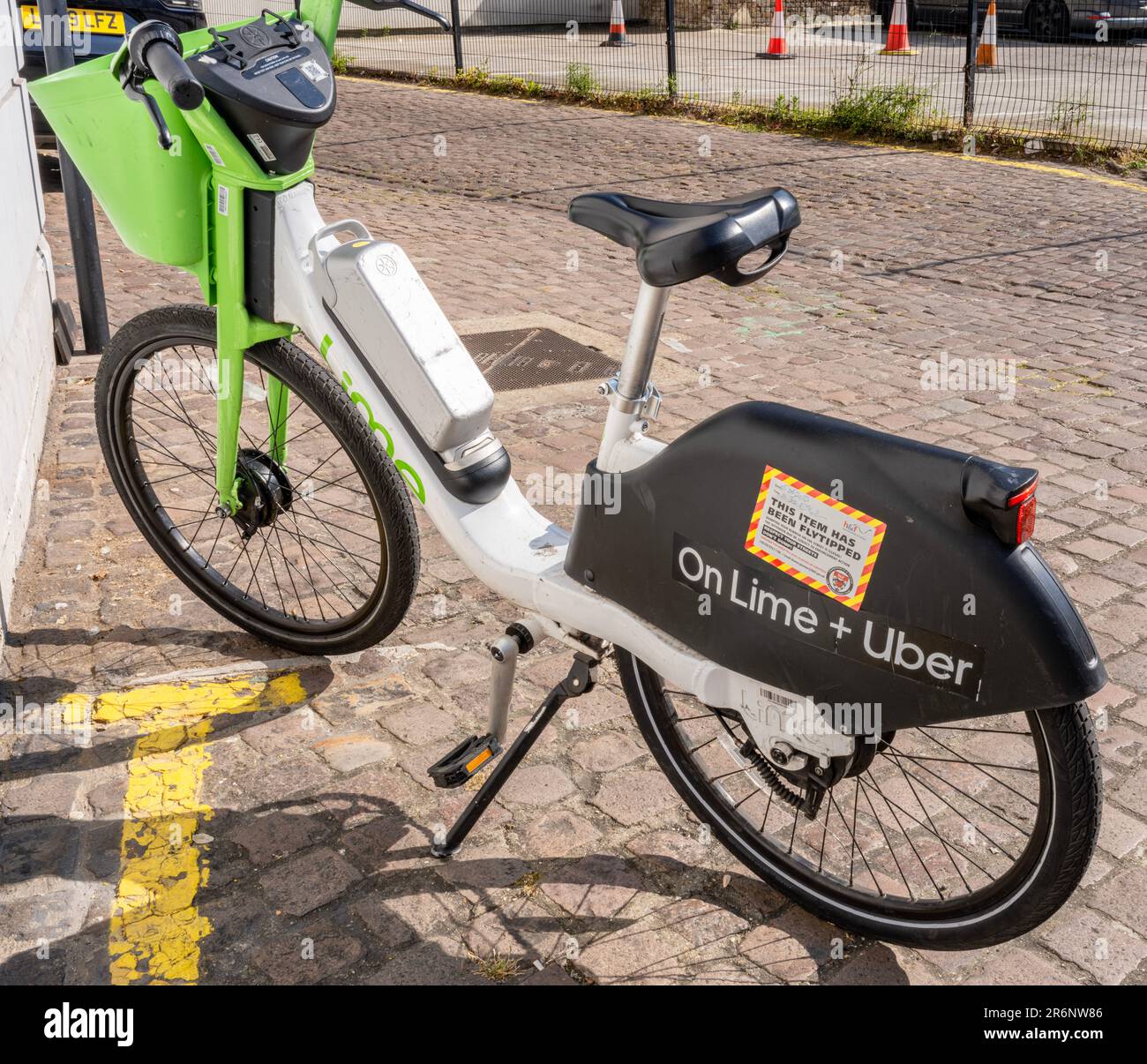 Bicicletta elettrica calce/Uber parcheggiata illegalmente ed etichettata con un avviso di 'flytipping' un disturbo pubblico Foto Stock