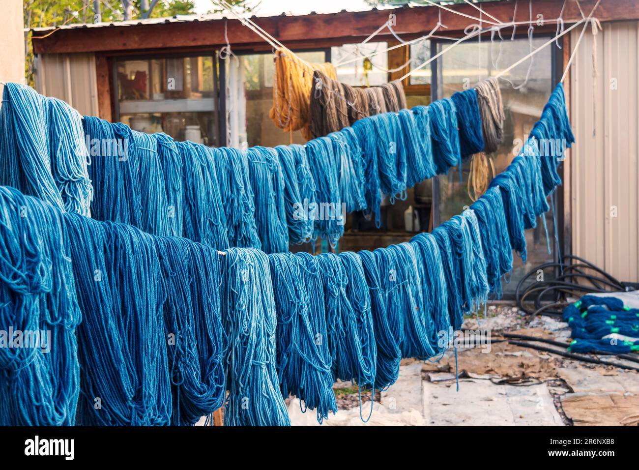 Matasse colorate di filato tinto a mano si asciugano su linee di corda in un cortile all'aperto presso il negozio di tessitura Trujillo a Chimayo, New Mexico, USA. Foto Stock