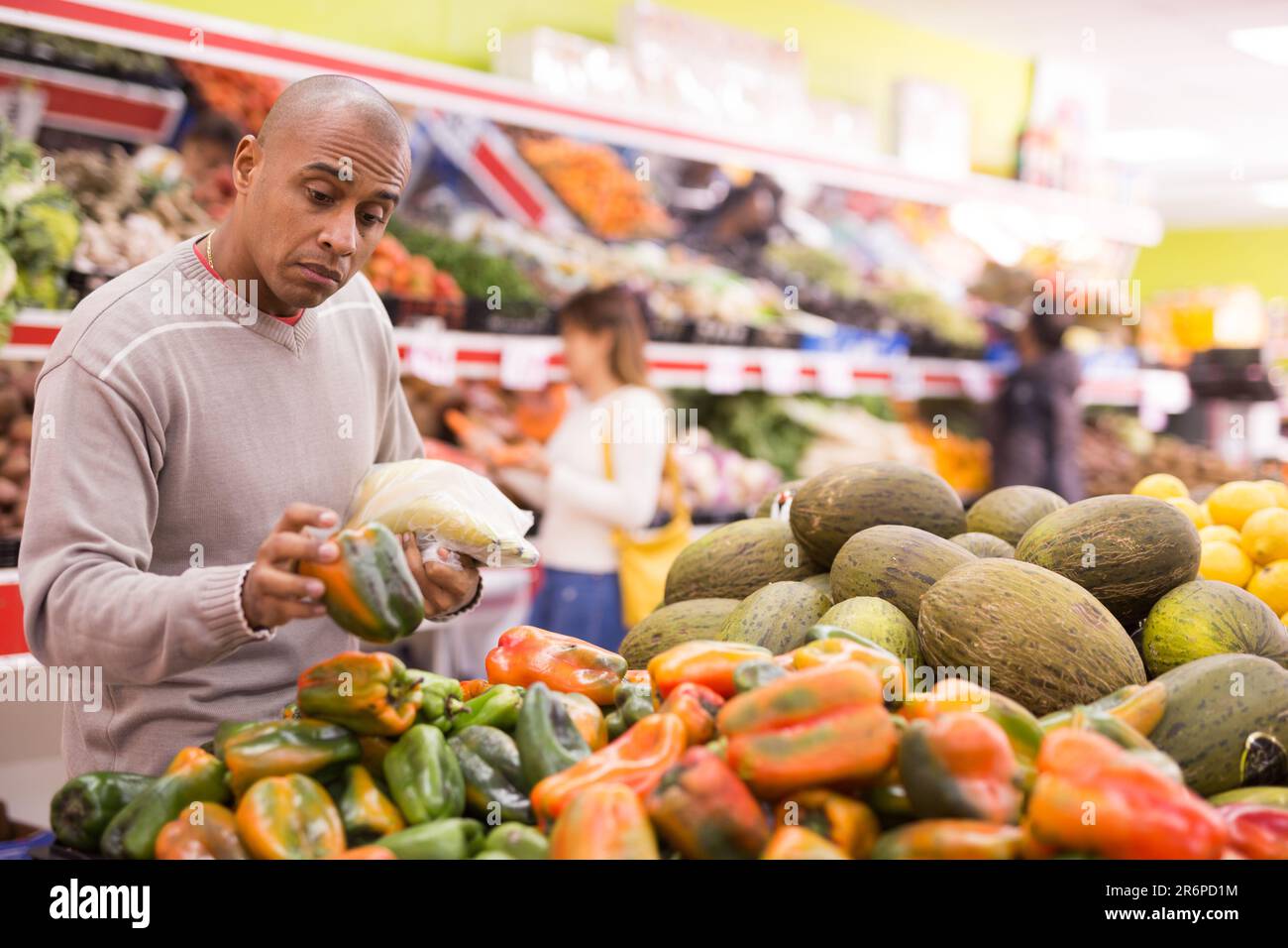 Il compratore seleziona i peperoni maturi nella sezione di verdure del supermercato Foto Stock