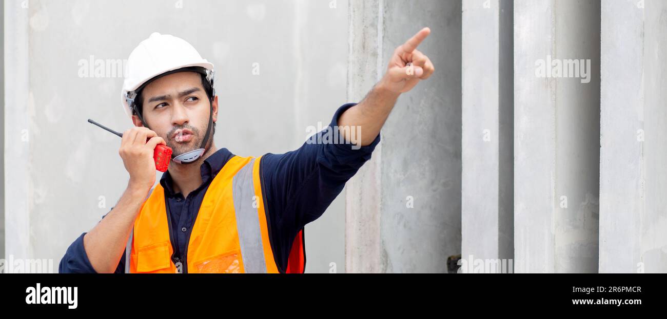 Un giovane ingegnere che utilizza il comando radio con un lavoratore in cantiere, architetto o appaltatore parla con la radio per il controllo e la pianificazione dello sviluppo Foto Stock