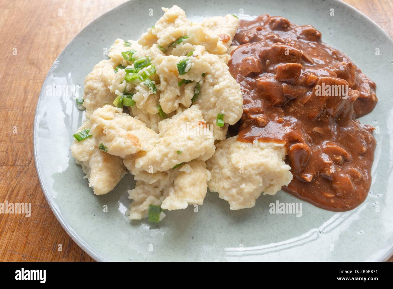 Immergetevi nei confortanti aromi e sapori dei nostri gnocchi fatti in casa, ripieni di saporito stufato di manzo e presentati su un delizioso piatto. Foto Stock