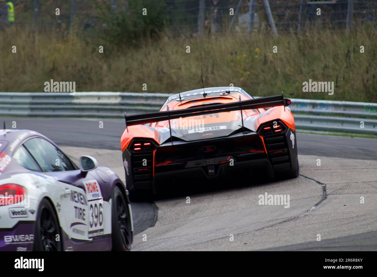 Un'auto da corsa arancione che guida su una pista, perfetta per qualsiasi sport motoristico o grafica correlata alle corse Foto Stock