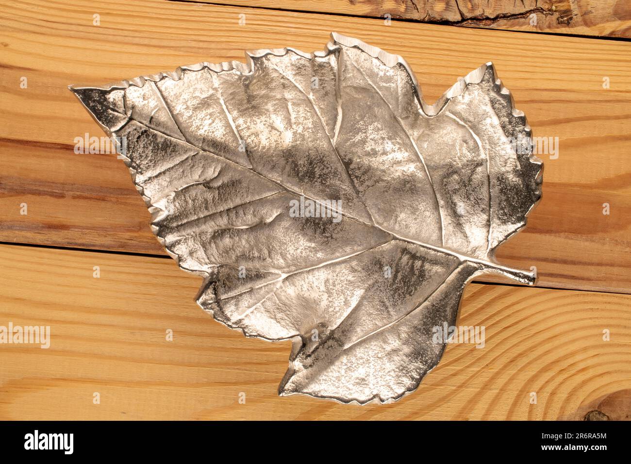 Un vaso in metallo a forma di foglia su un tavolo di legno, vista dall'alto. Foto Stock