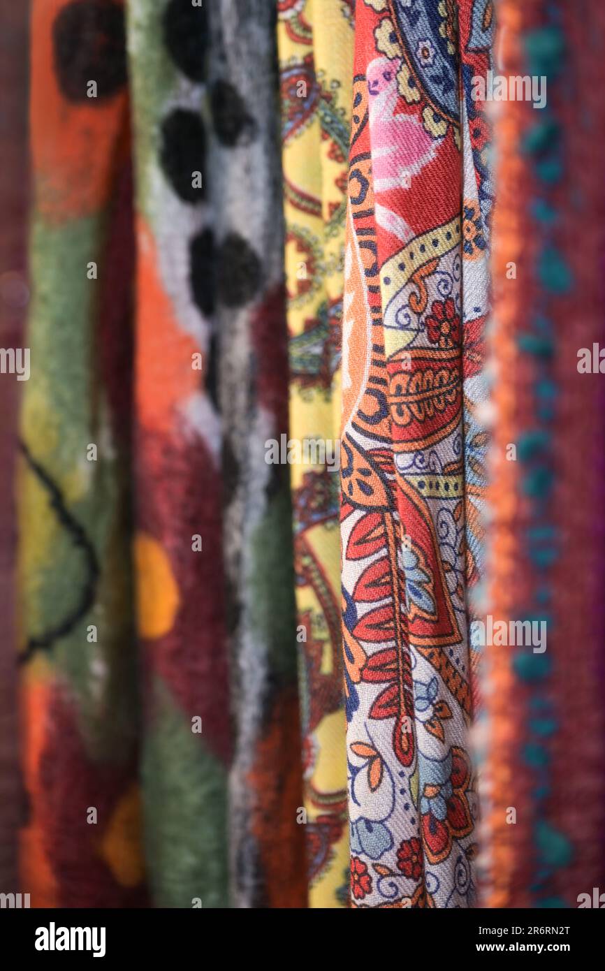 Tessuti di lana tessuti con diversi motivi colorati più in tonalità rosse appesi per la vendita in un negozio, spazio copia, fuoco selezionato, profondità molto stretta di fiel Foto Stock