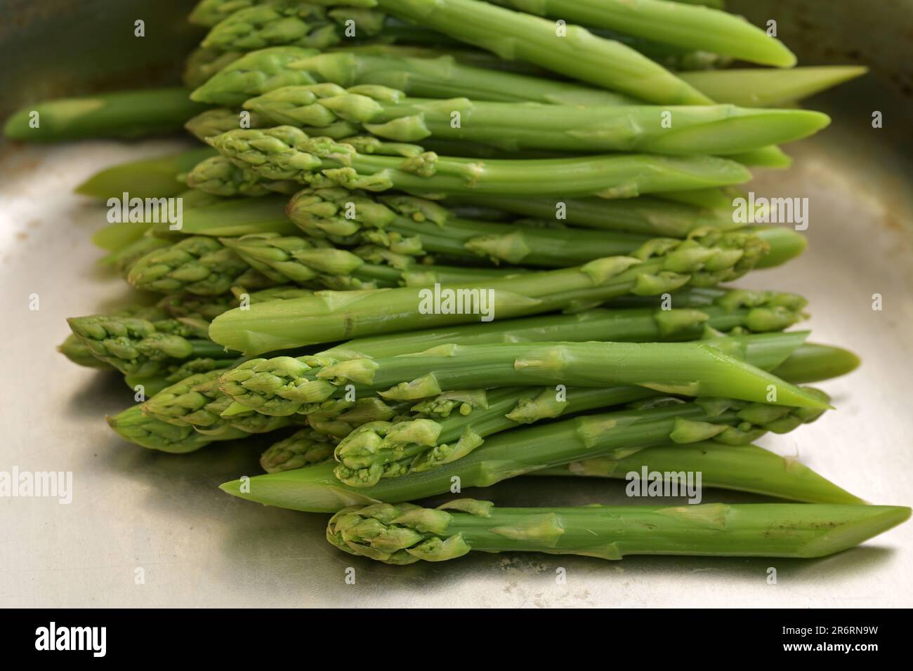 Asparagi verdi sbolliti in un contenitore metallico, cucina con verdure di stagione sane, focus selezionato, profondità di campo ristretta Foto Stock