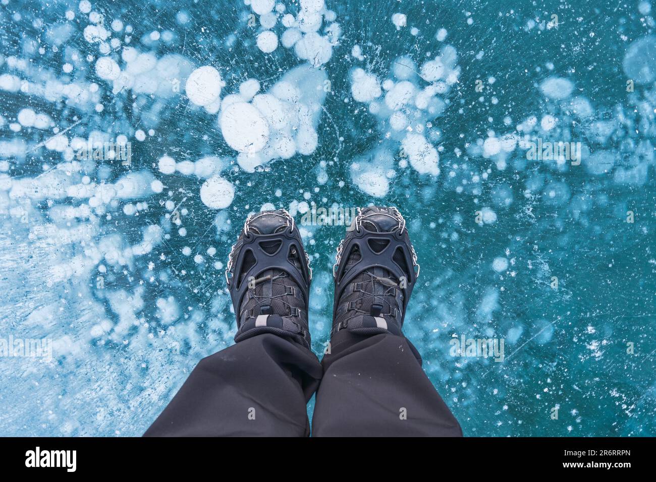 Uomo in stivali in piedi sul lago ghiacciato con bolla naturale in inverno in Canada Foto Stock
