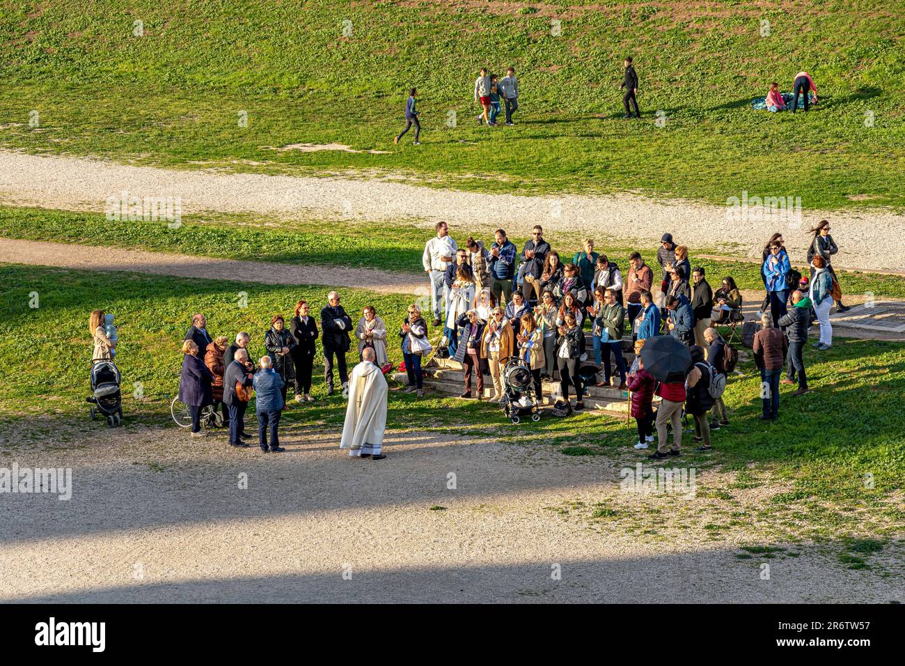 Una piccola folla di persone partecipa a un raduno religioso al Circo massimo, un'antica pista romana di carri, Roma Italia Foto Stock