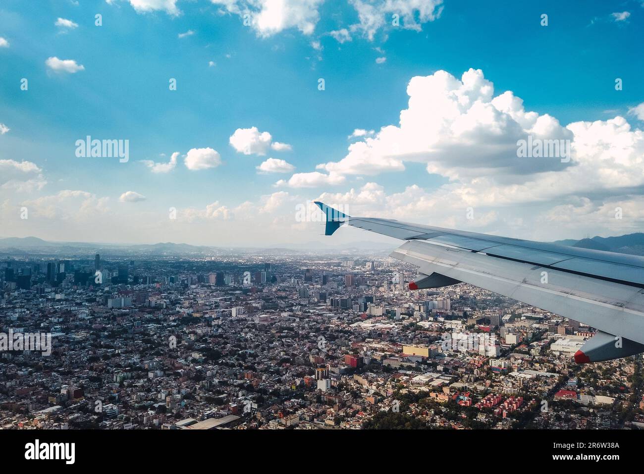 Un aereo sorvola con grazia il vivace paesaggio urbano, collegando orizzonti distanti e ponendosi a ponte tra i regni di possibilità e avventura nell'urbano la Foto Stock