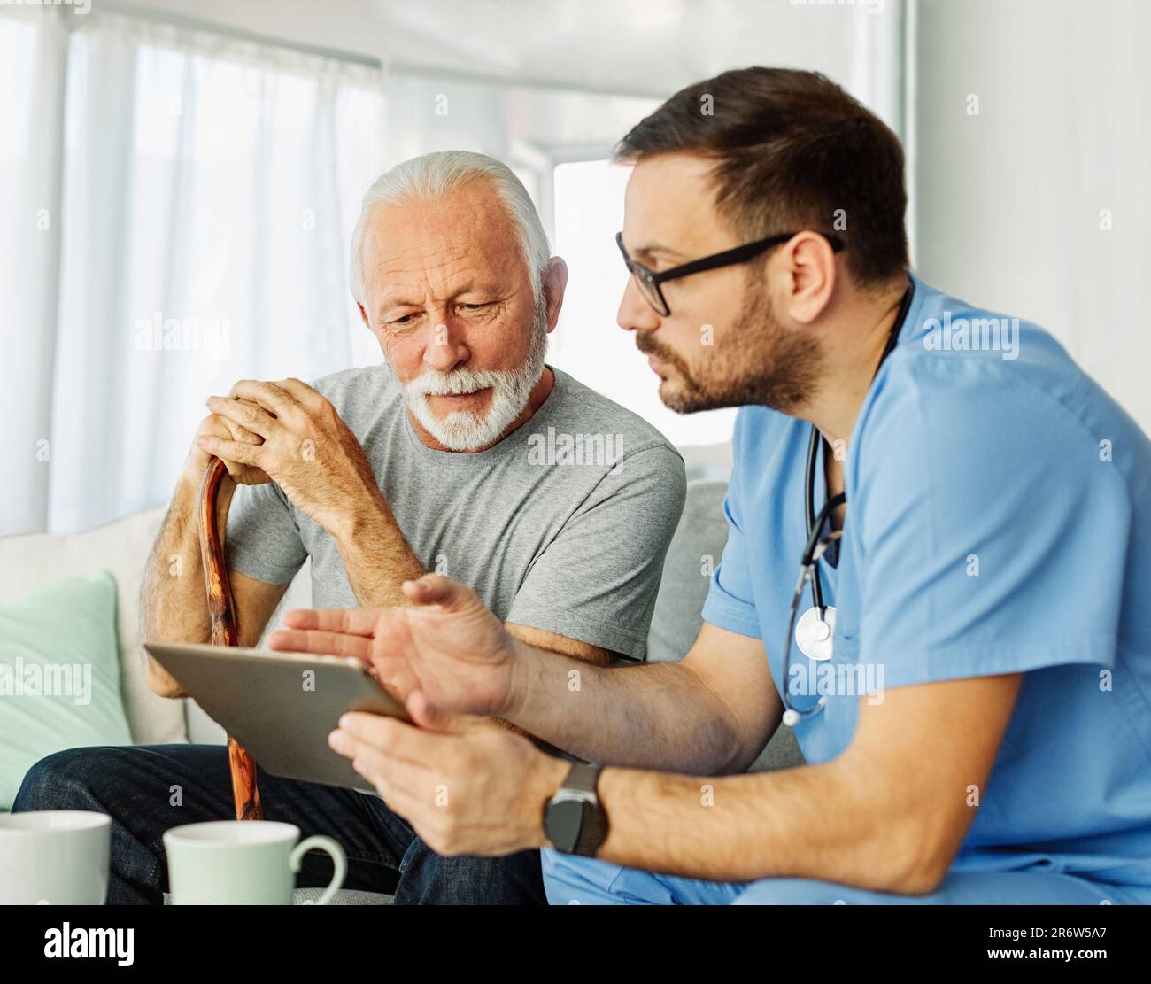 medico infermieristico assistenza senior tablet tecnologia che mostra caregiver aiuto assistenza pensione casa infermieristica anziani felice ridere uomo Foto Stock