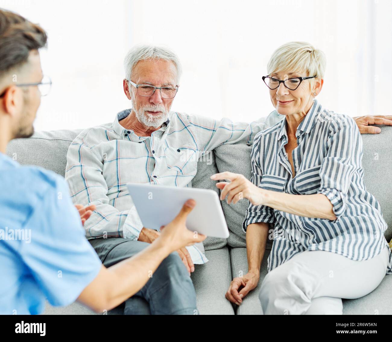 infermiera medico anziano cura di coppia caregiver aiuto pensione assistenza casa infermieristica anziano uomo donna tablet tecnologia Foto Stock
