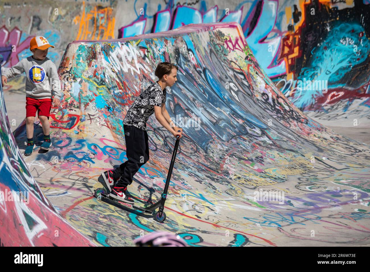Boy scooting al Suvilahti DIY Skatepark coperto da graffiti a Helsinki, Finlandia Foto Stock