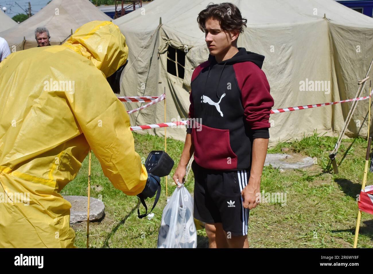 Un lavoratore di emergenza ucraino che indossa un vestito di protezione dalle radiazioni controlla un adolescente con dosimetro durante un addestramento di esposizione alle radiazioni in caso. L’agenzia Ucraina per l’energia nucleare ha messo l’ultimo reattore in funzione della centrale nucleare di Zaporizhzhia, considerata la più grande centrale nucleare europea, in una “chiusura a freddo” come mossa precauzionale dopo la distruzione della diga di Kakhovka, l’agenzia ha affermato che nella dichiarazione di venerdì. Foto Stock