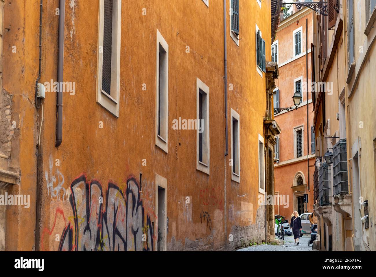 Una donna che cammina lungo una strada stretta a Roma, in Italia Foto Stock
