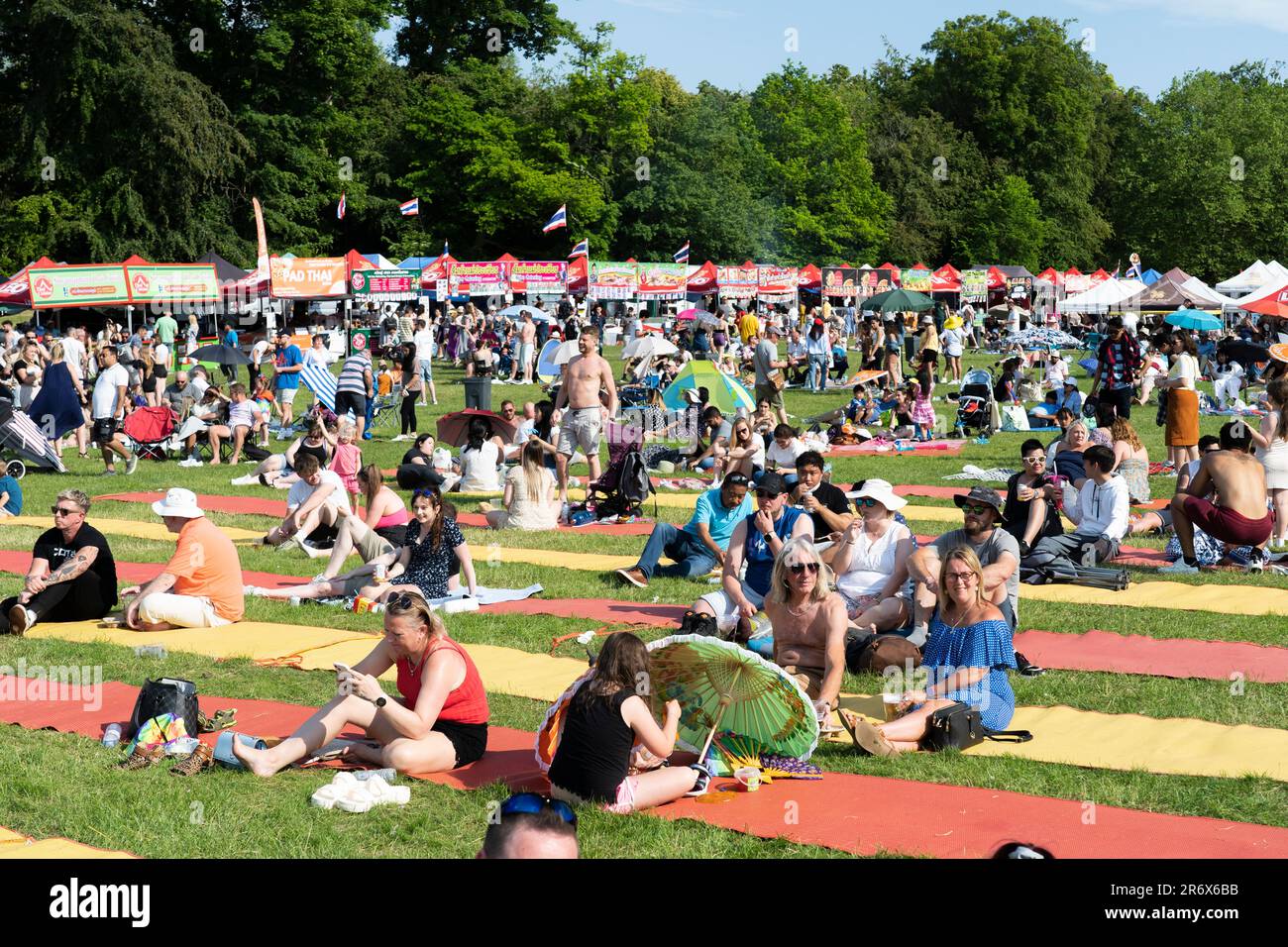 Le persone che si siedono e si godono il sole estivo al Magic of Thailand Festival al Basingstoke War Memorial Park. Giugno 10th 2023. Inghilterra Foto Stock