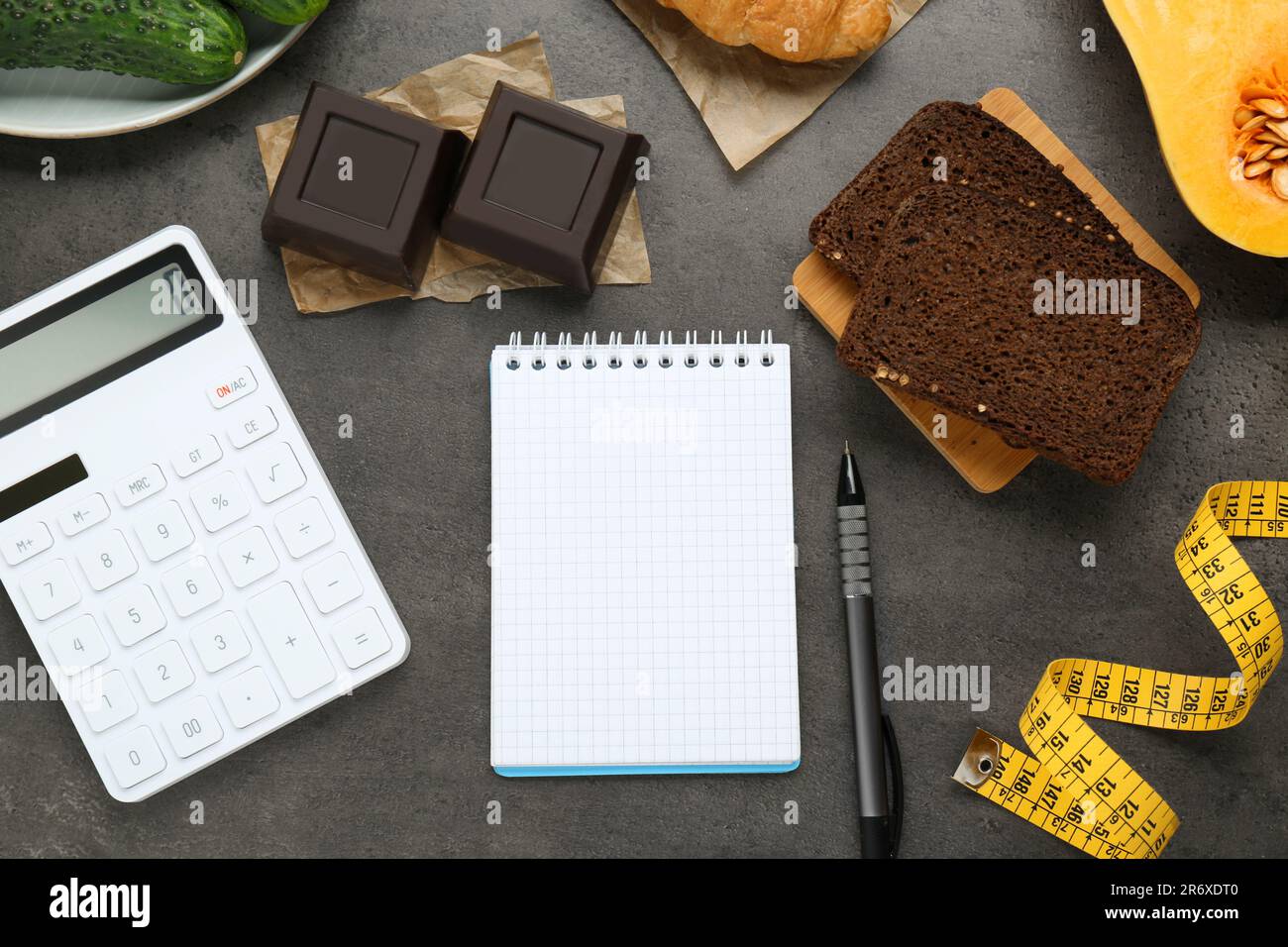 Prodotti alimentari, notebook con calcolatrice su tavolo grigio scuro, piatto. Concetto di perdita di peso e conteggio delle calorie Foto Stock