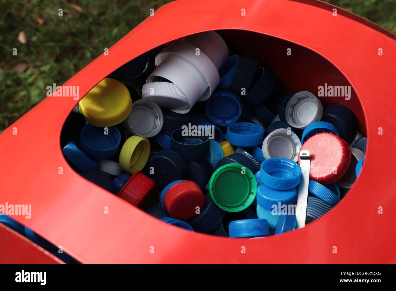 Diversi tappi colorati per bottiglie in contenitore rosso. Riciclaggio della plastica Foto Stock