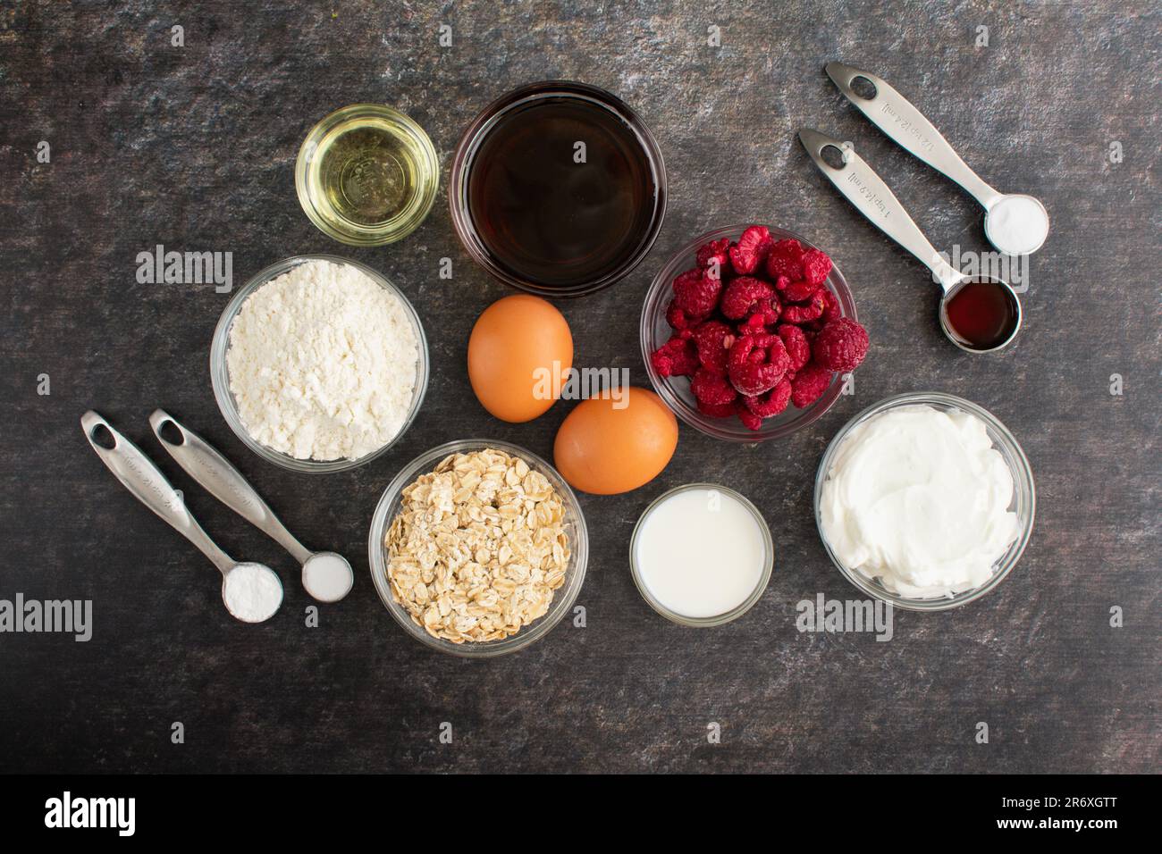Muffin al lampone sani ingredienti su sfondo scuro: Lamponi congelati, farina e altri ingredienti utilizzati per rendere i muffin più sani Foto Stock