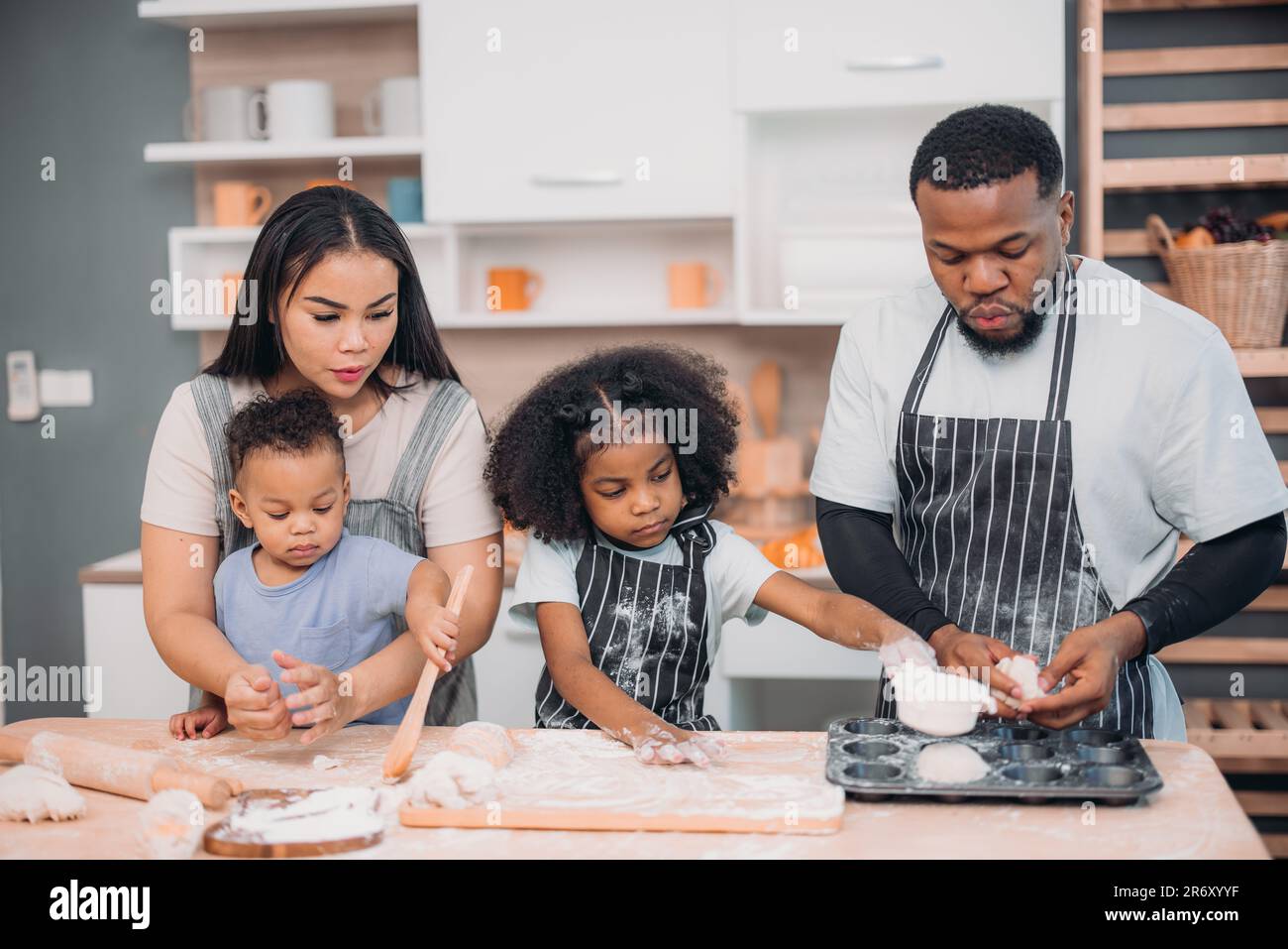 I membri della famiglia cucinano pasta fatta in casa per pizza in modi divertenti e divertenti. Mescolare ingredienti come sale, zucchero, latte, lievito, olio e strofinare, massaggio, pre Foto Stock