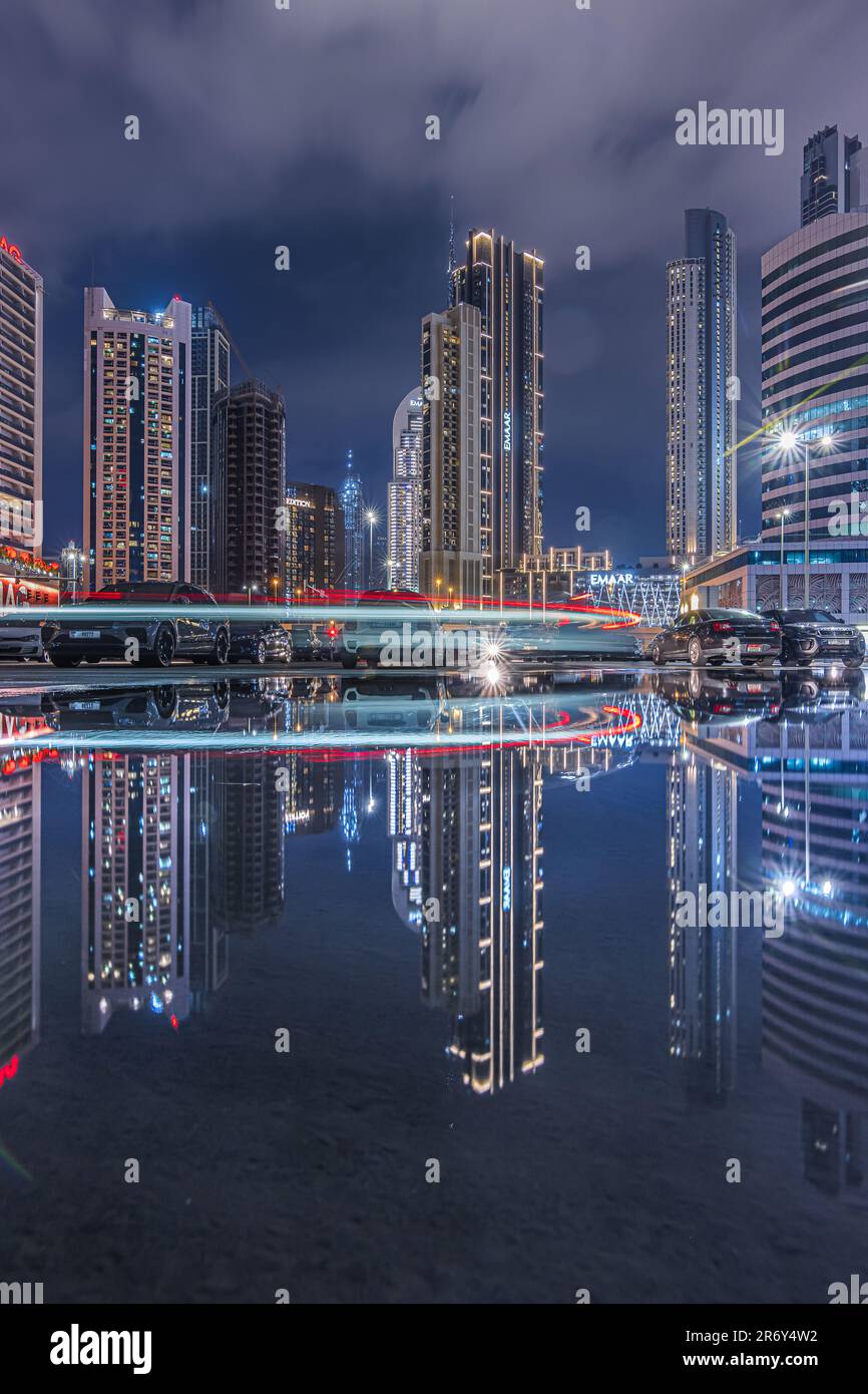 Edifici di uffici nel centro di Dubai di notte. Grattacieli illuminati della città negli Emirati Arabi Uniti all'ora blu. Riflessi della luce Foto Stock