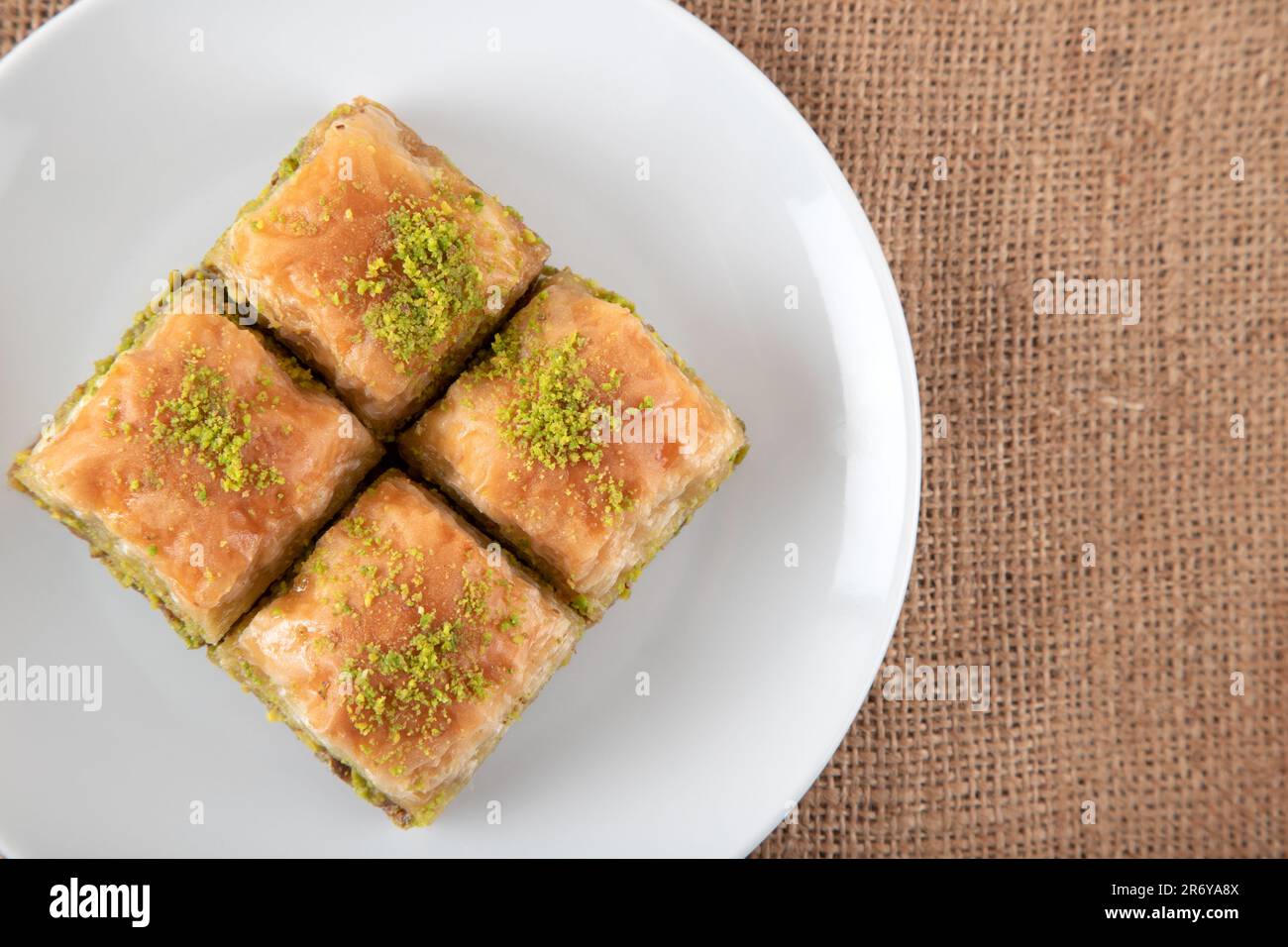 Tradizionale baklava pistacchio in piatto bianco.A piatto baklava su sacco di burlap Foto Stock