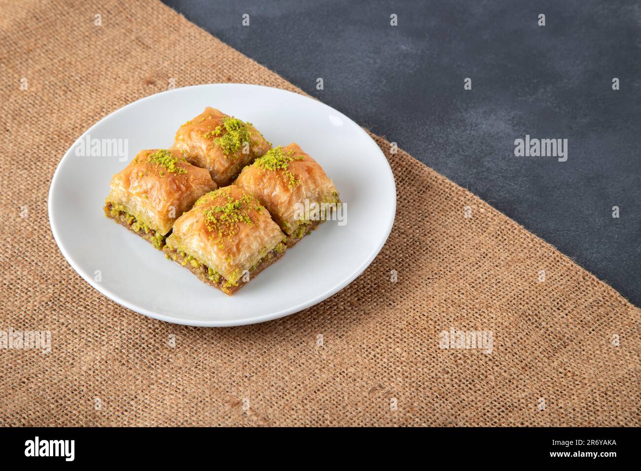 Tradizionale baklava pistacchio in piatto bianco.A piatto baklava su sacco di burlap Foto Stock