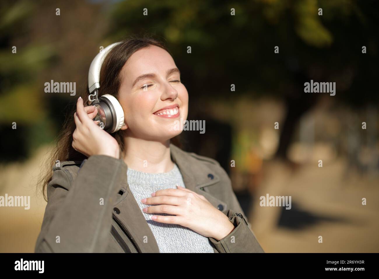 Donna felice che cammina e ascolta musica con le cuffie Foto Stock
