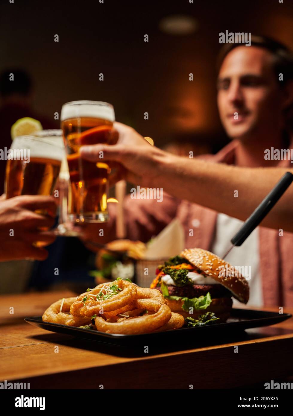 Primo piano di giovani amici multirazziali in abbigliamento casual gustando fast food e birre al bar Foto Stock