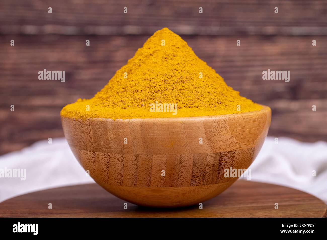 Polvere di curry su sfondo di legno. Curry in polvere in ciotola di legno. Miscela di spezie ed erbe essiccate. Concetto di spezia. Primo piano Foto Stock