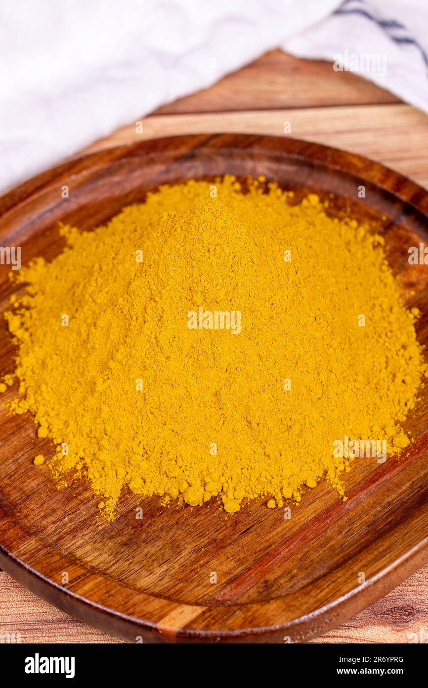 Polvere di curry su sfondo di legno. Curry in polvere in ciotola di legno. Miscela di spezie ed erbe essiccate. Concetto di spezia Foto Stock