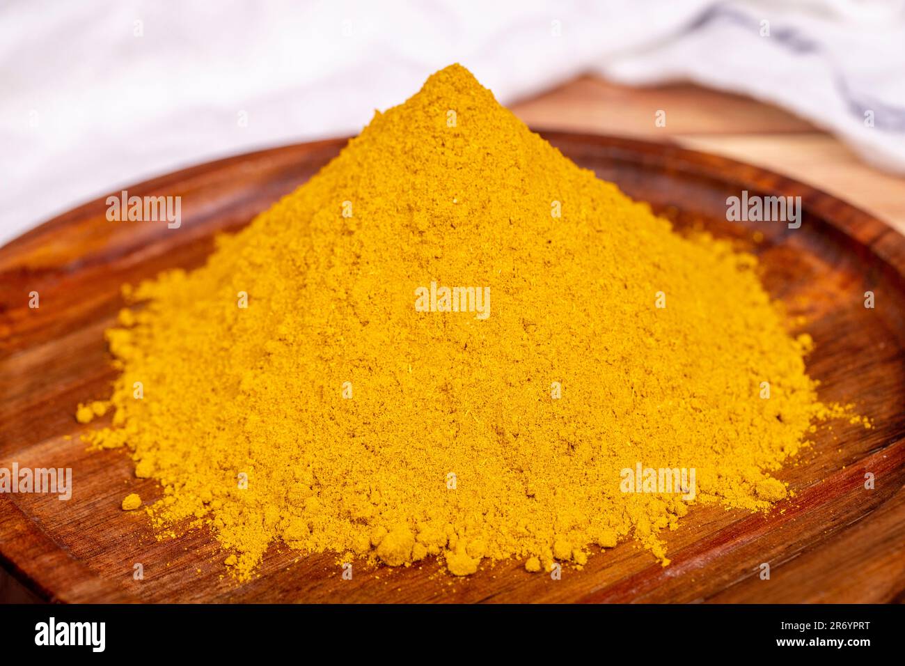Polvere di curry su sfondo di legno. Curry in polvere in ciotola di legno. Miscela di spezie ed erbe essiccate. Concetto di spezia. Primo piano Foto Stock