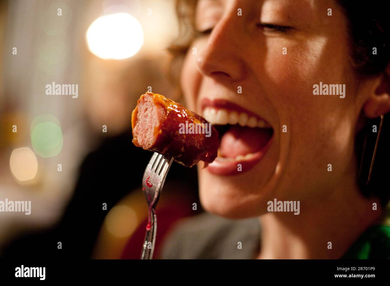 Una donna tiene una salsiccia polacca con una forchetta mentre la muta in un ristorante polacco a Seattle, Washington. Foto Stock