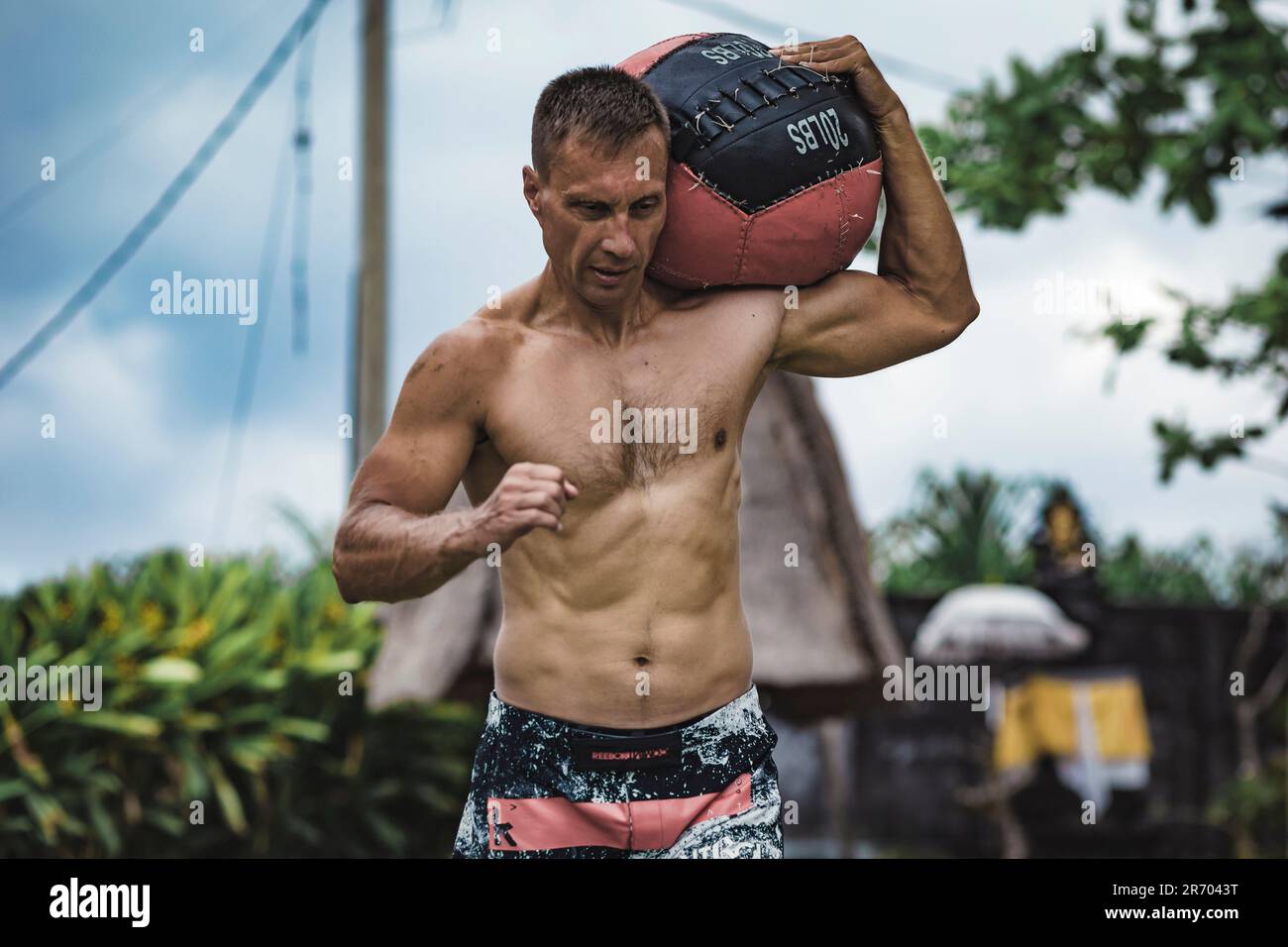 Uomo che si esercita con la palla medica, Canggu, Bali, Indonesia Foto Stock