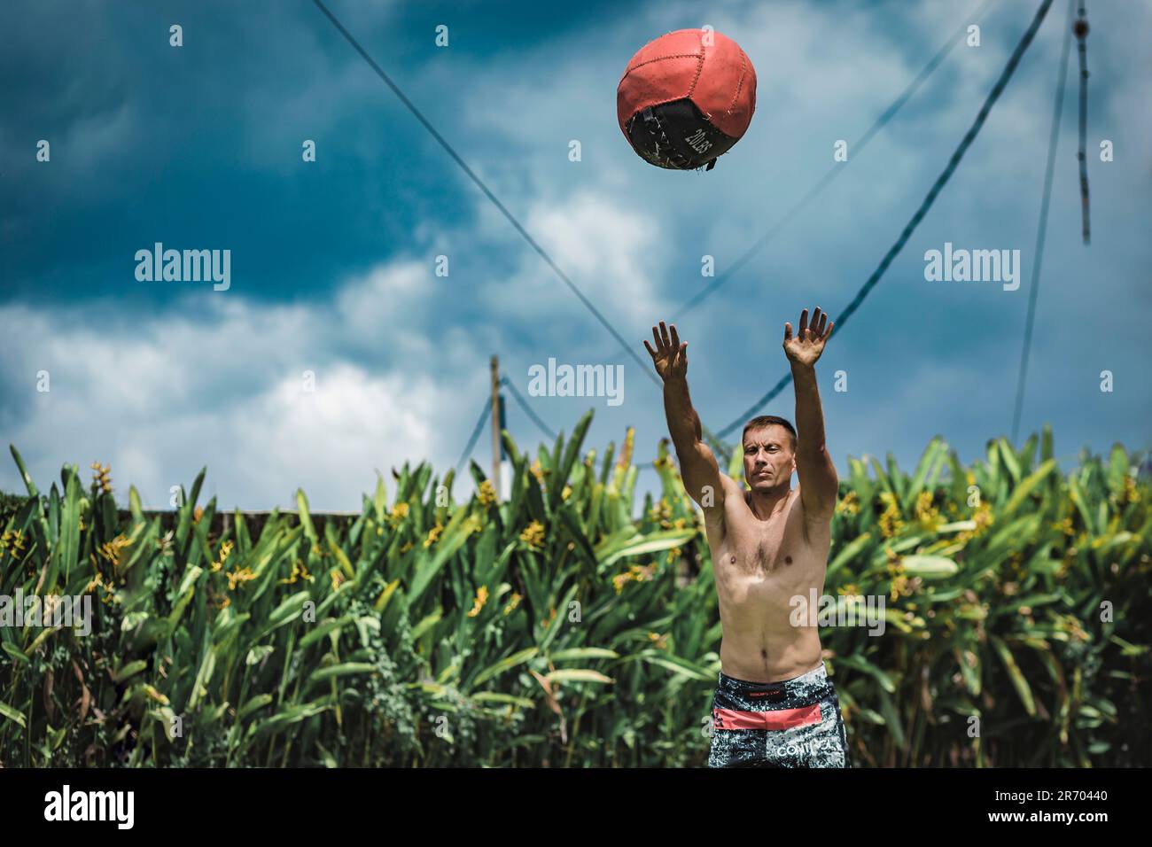Uomo che si esercita con la palla medica, Â Canggu, Bali, Indonesia Foto Stock