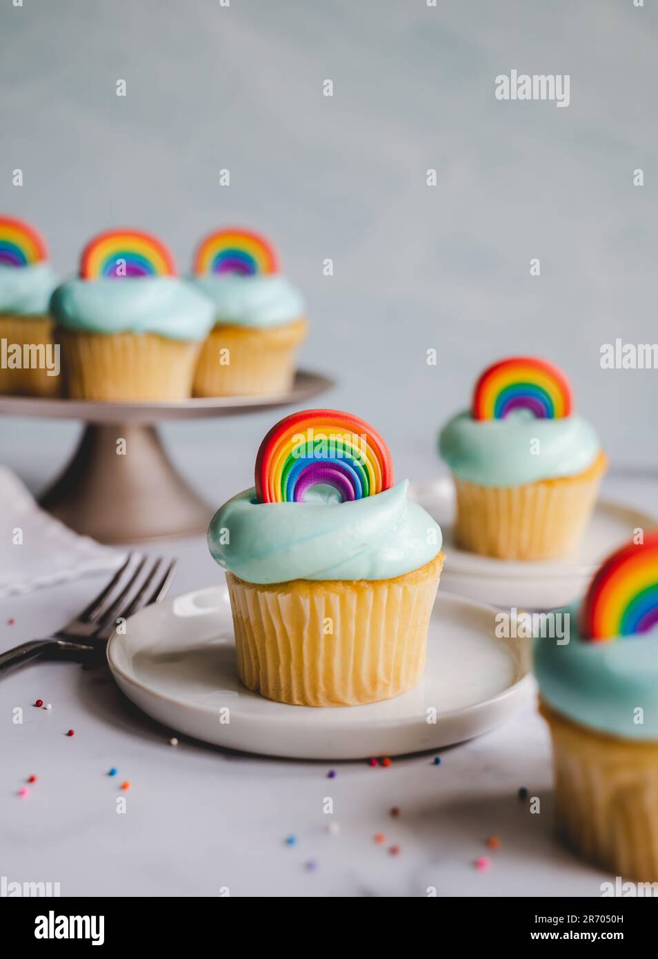 Cupcake alla vaniglia decorati con arcobaleno di orgoglio su sfondo bianco. Foto Stock