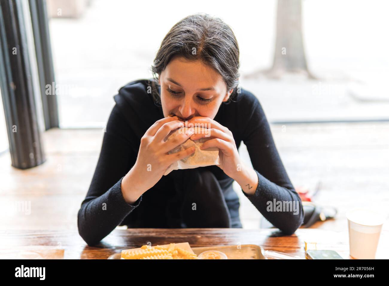 giovane donna che mangia un menu di hamburger nel ristorante Foto Stock