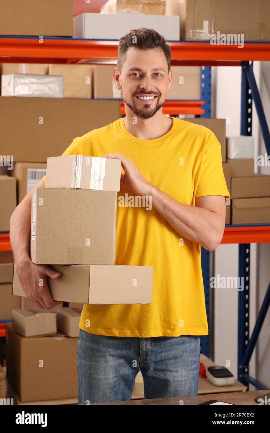 Addetto all'ufficio postale con pacchi vicino al rack interno Foto Stock