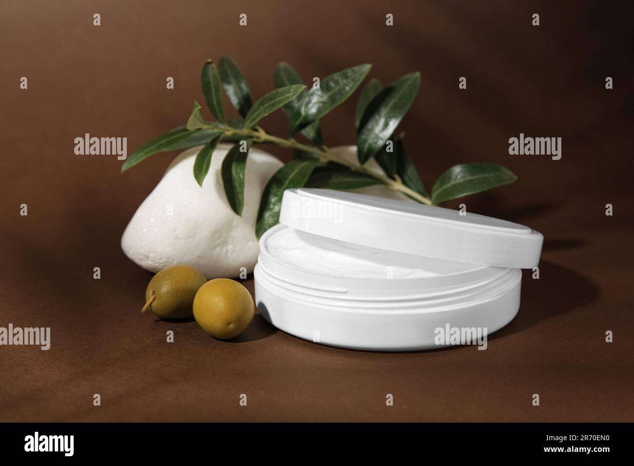 Vasetto di crema naturale, pietra e olive su fondo marrone. Prodotti cosmetici Foto Stock