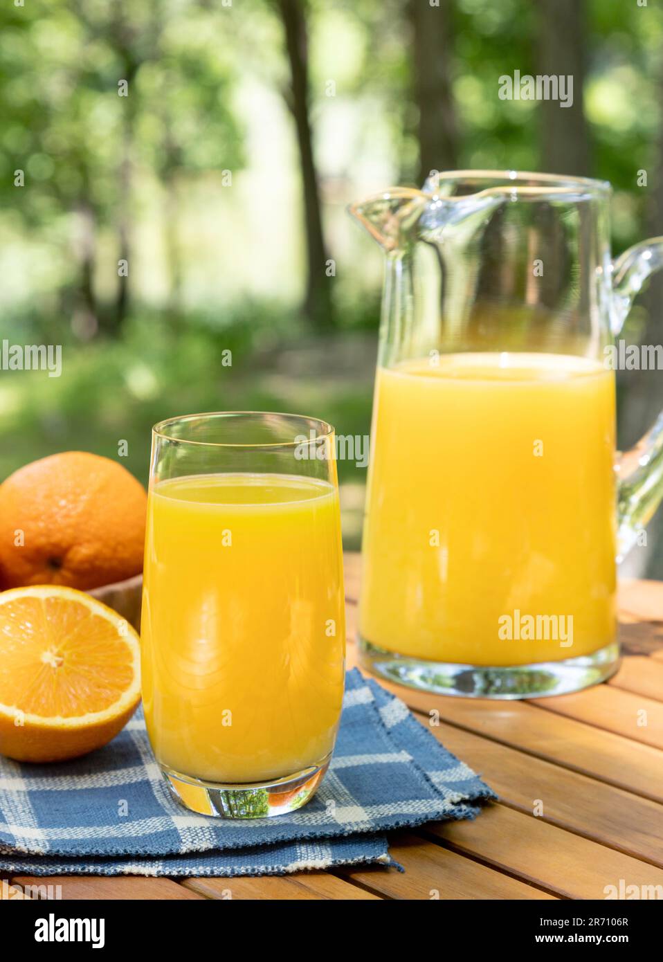 Bicchiere di succo d'arancia e arance all'aperto su un tavolo di legno con sfondo naturale Foto Stock