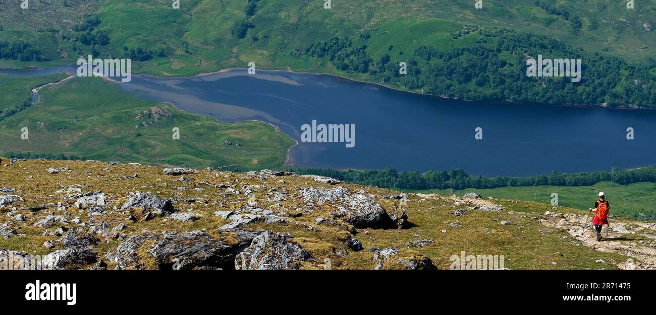 Una sola ragazza escursionista che scende lungo un percorso accidentato da ben More verso il Loch Iubbair in Glen Dochart Foto Stock